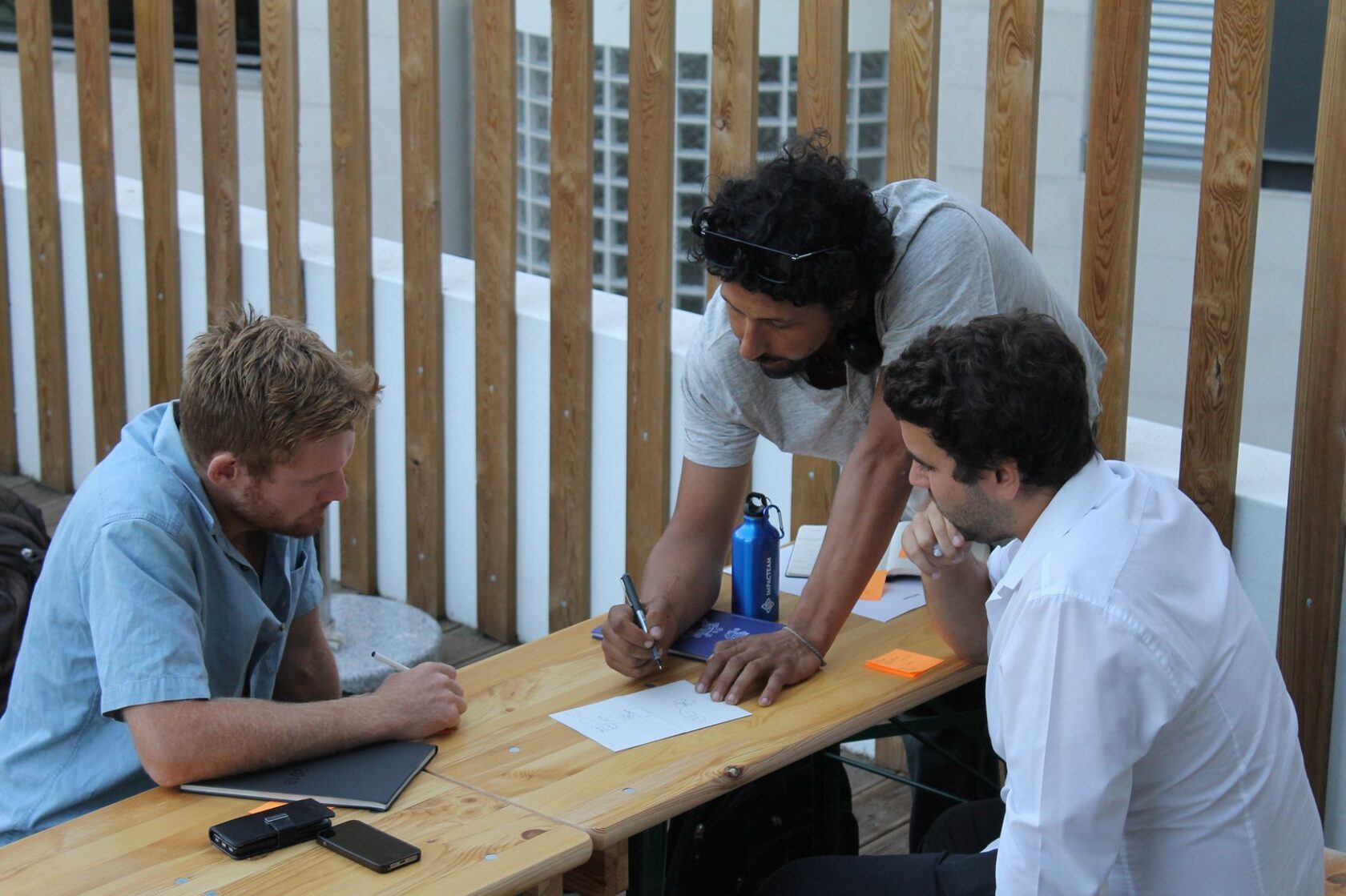 Richard Kappel writing at a table with two collaborators